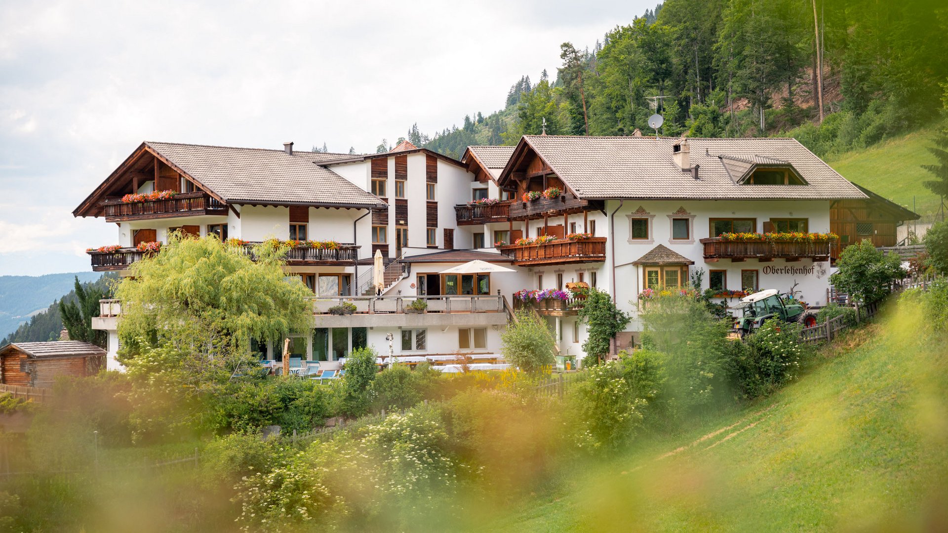 Zu Hause bei uns: das Hotel Oberlehenhof bei Deutschnofen Gästehaus in den grünen Bergen mit Blumen verzierten Balkonen